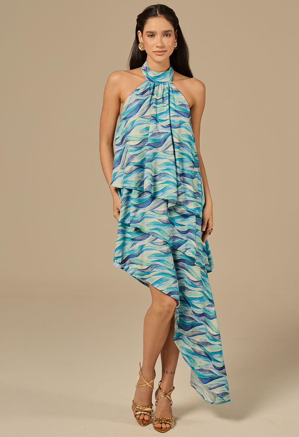 Modelo vestindo o Vestido Jamile Orla em tons de azul, turquesa e branco, com caimento assimétrico e gola halter
