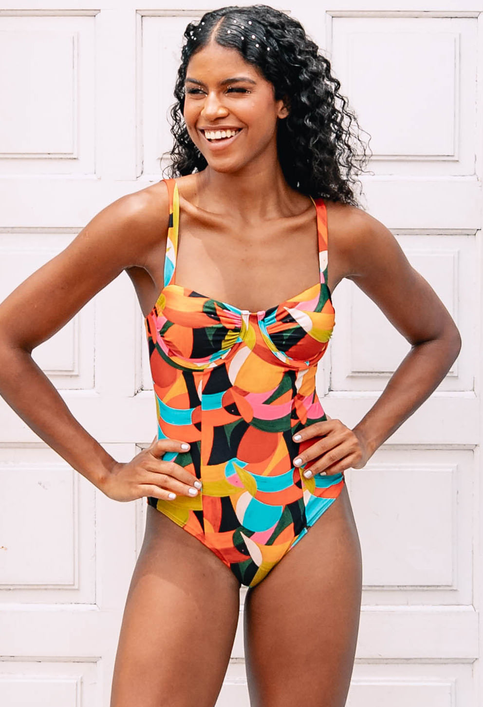 Modelo usando Body Evelin Borogodó com estampa geométrica vibrante em tons de laranja, amarelo, rosa, azul e verde