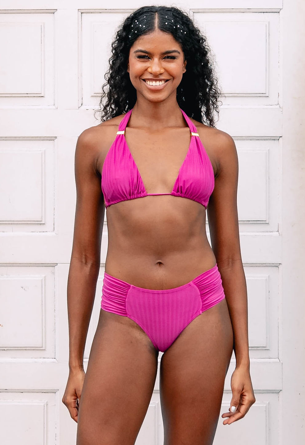 Calcinha Borboleta Larga Mar de Rosas frente em rosa vibrante, modelo em porta branca