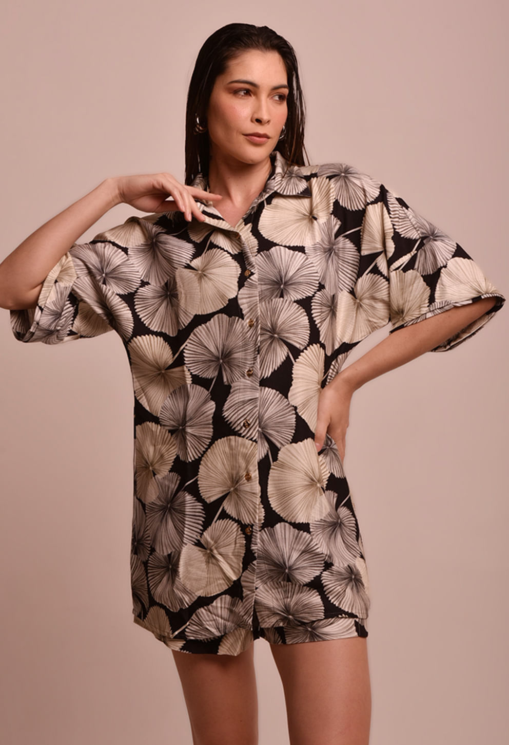 Modelo feminina veste camisão longo com estampa de grandes mandalas em tons creme e bege sobre base preta. Corte oversized, botões frontais, gola polo e mangas amplas 3/4. Tecido leve com caimento flu