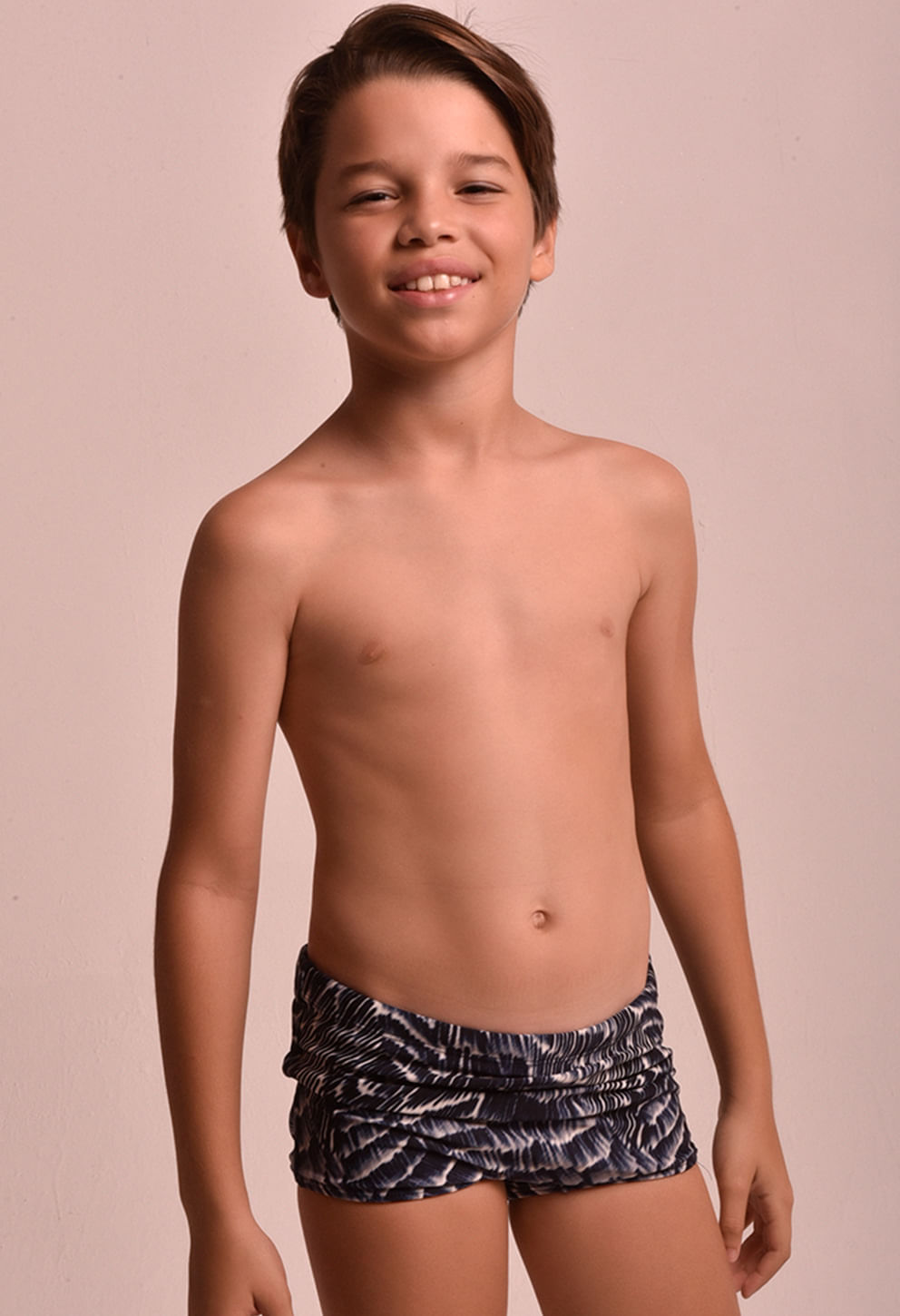 Menino posando em estúdio usando sunga infantil Maré Alta preta e branca, cós elástico e franzidos laterais