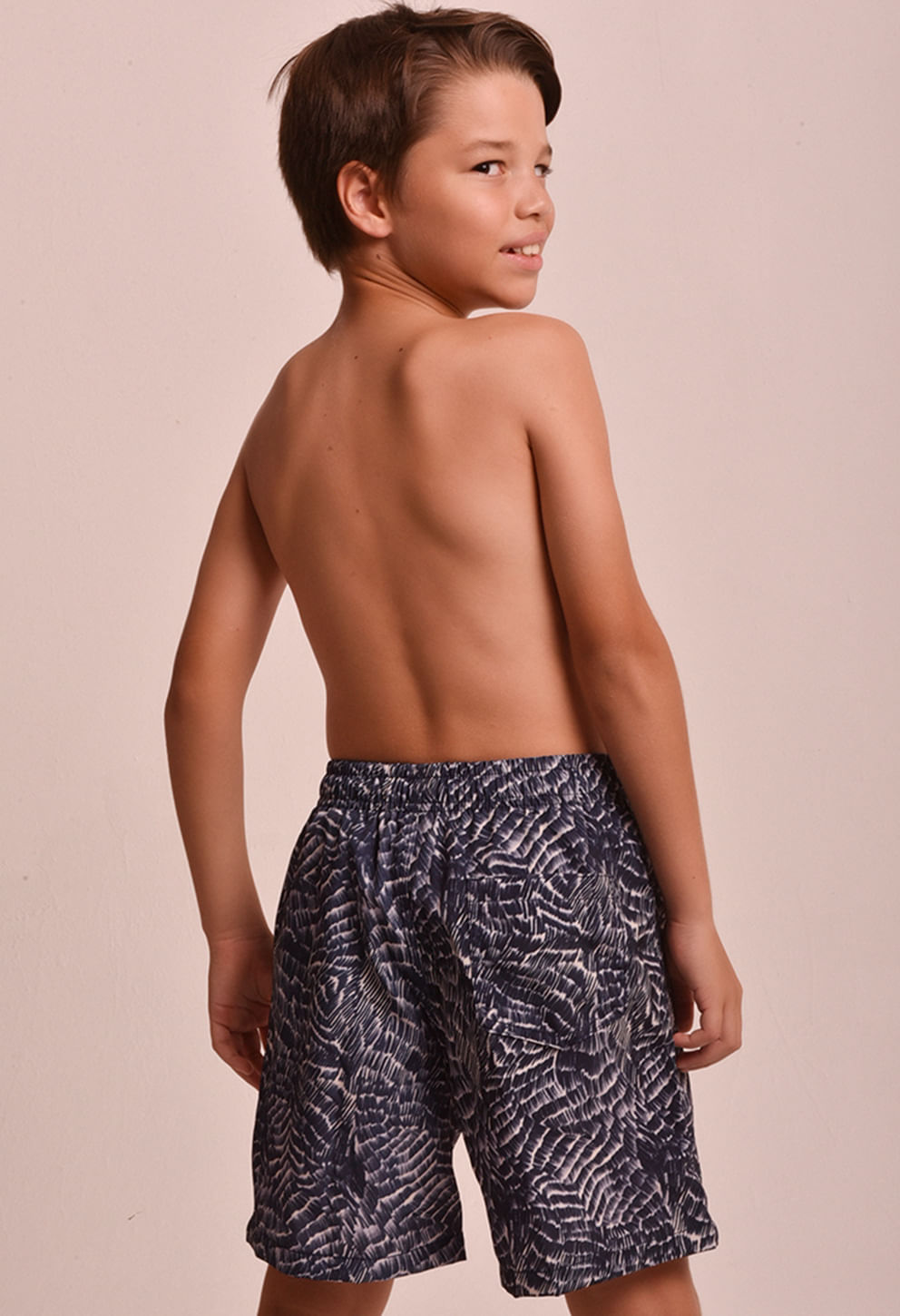 Menino de costas usando bermuda infantil azul escura com estampa abstrata e cós elástico