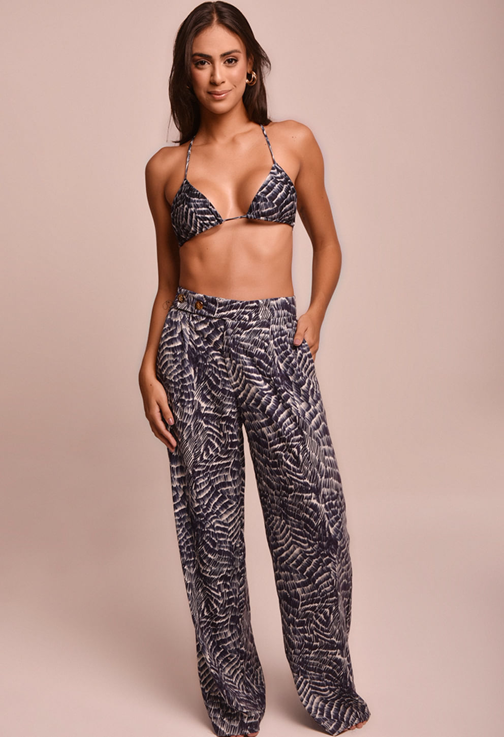 Modelo usando calça pantalona azul e branca com cós assimétrico e botões dourados