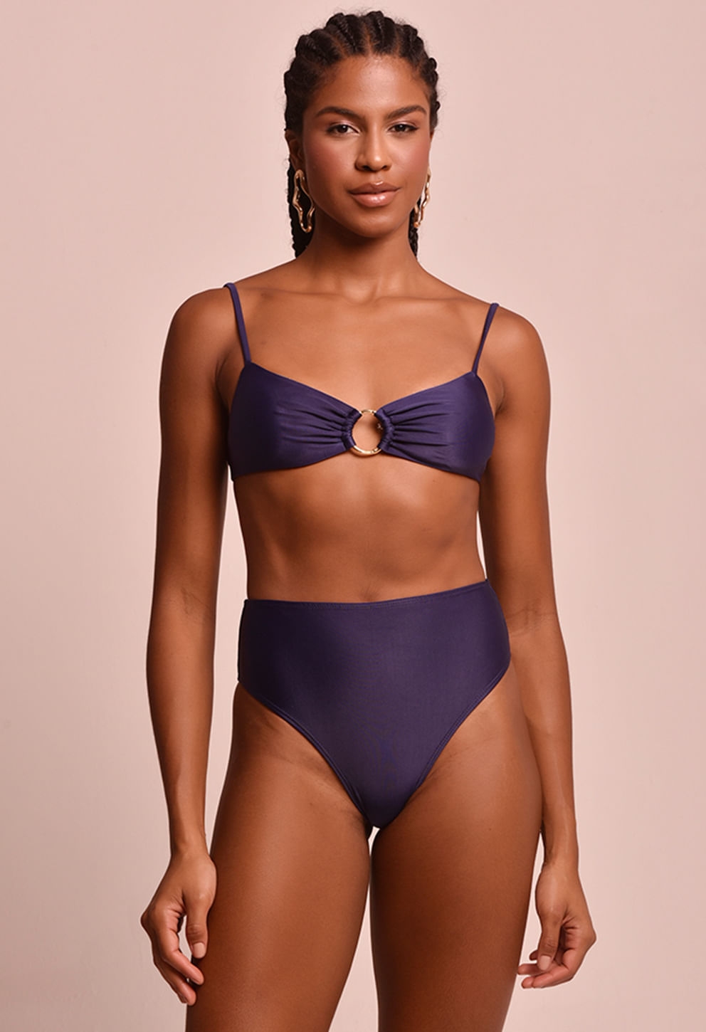 Modelo feminina usando biquíni azul marinho com calcinha hot pant de cintura alta, vista frontal, fundo bege claro.