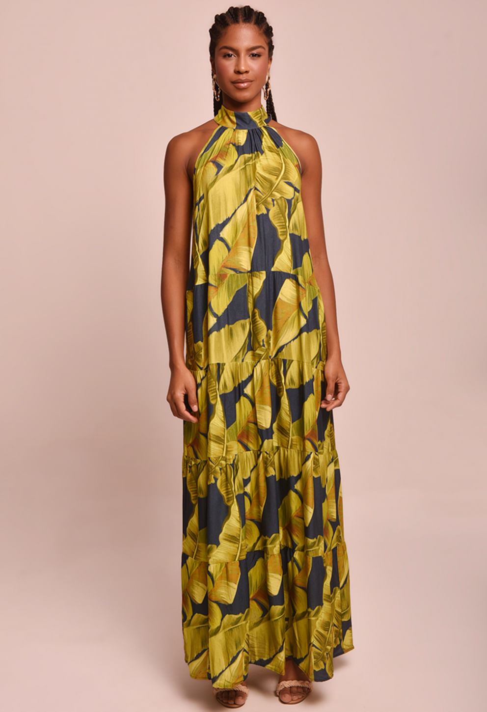 Vestido longo estampado em tons de verde e amarelo, gola halter, babados em camadas e caimento fluido.