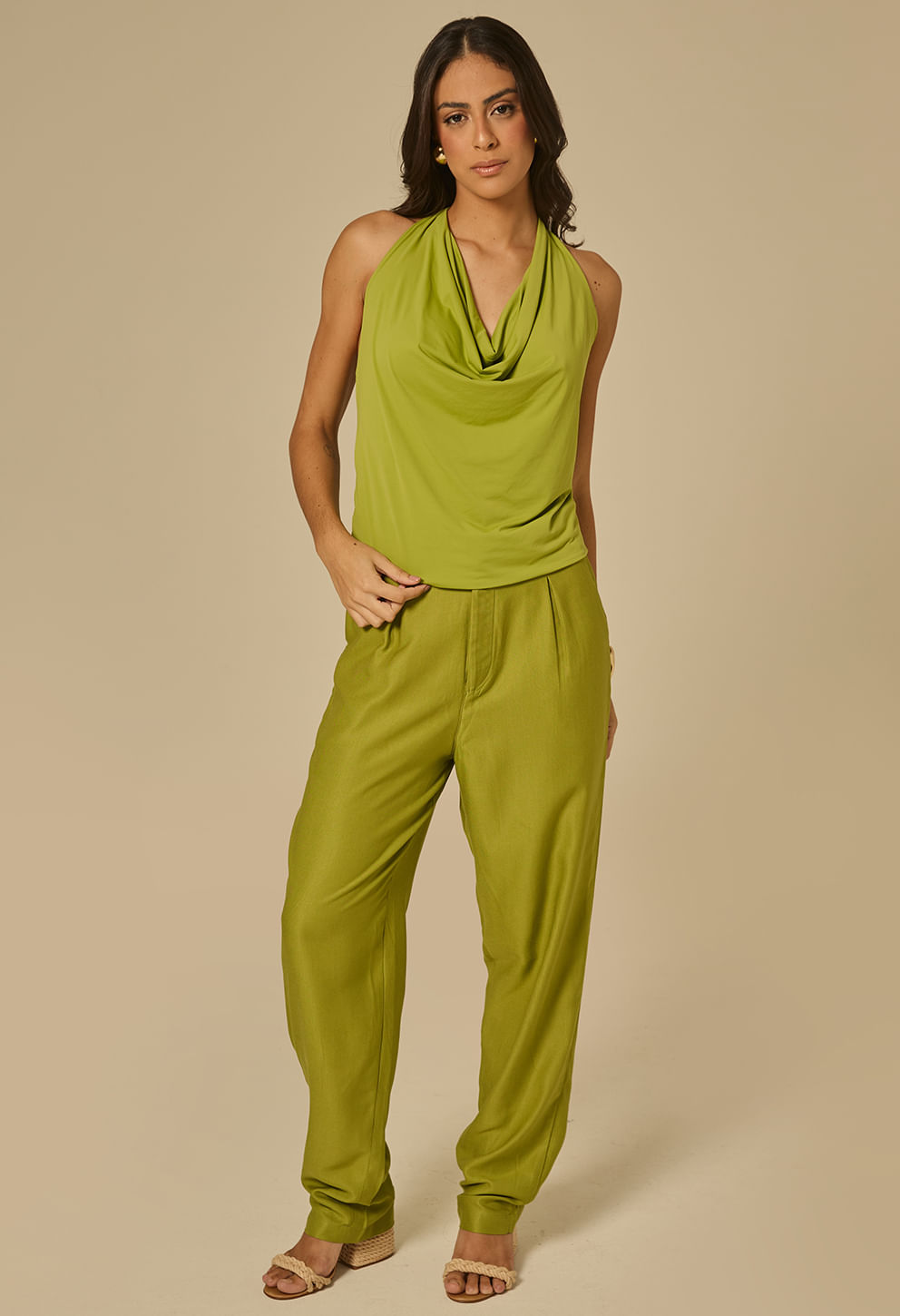 Modelo veste blusa verde esmeralda com decote drapeado e amarração no pescoço