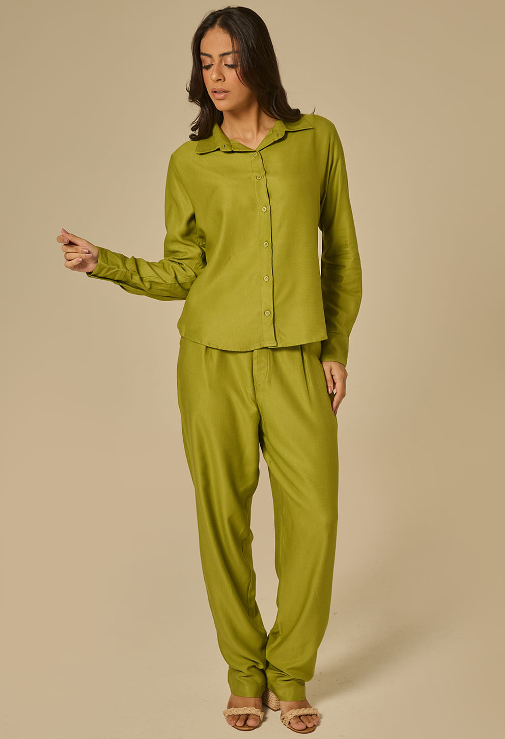 Modelo em estúdio usando camisa de botões verde esmeralda lisa com gola clássica e mangas longas abotoadas.