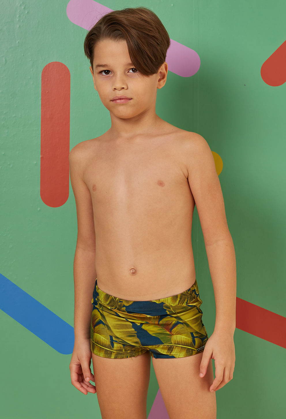 Sunga short infantil azul escuro com estampa tropical de folhas, vista frontal.
