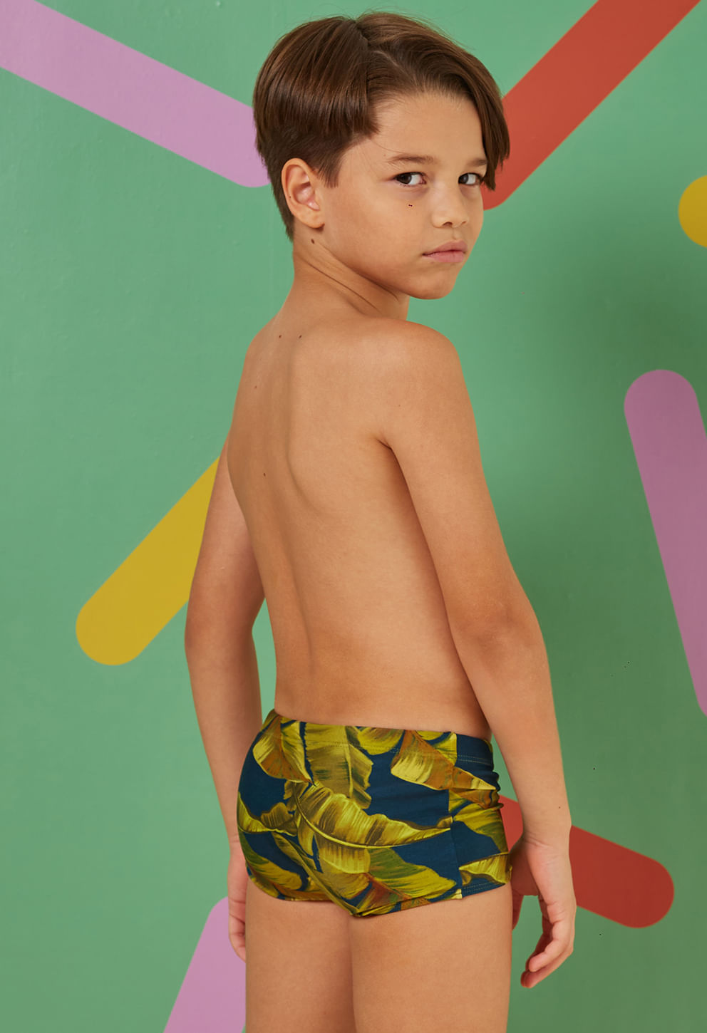 Sunga short infantil azul escuro com estampa de folhas vista de costas.