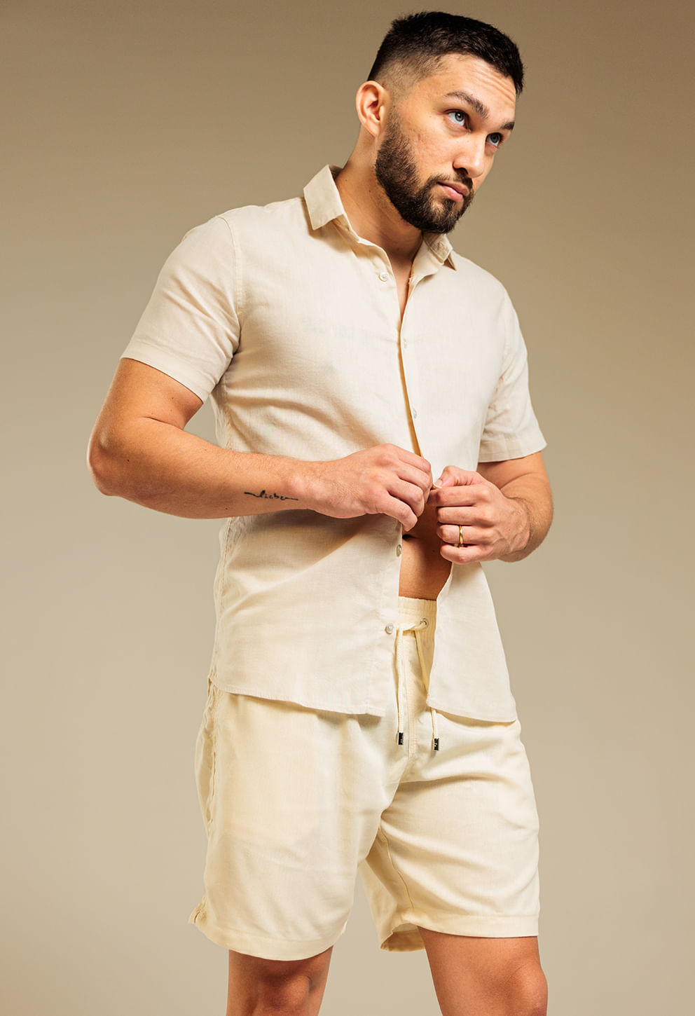 Homem vestindo bermuda casual de linho na cor natural/bege claro, vista frontal com camisa combinando