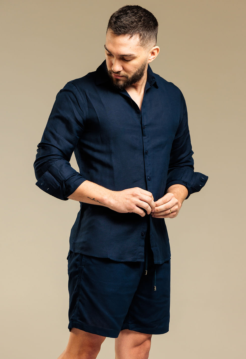 Homem vestindo bermuda casual em linho azul-marinho com cordão frontal e bolsos laterais e traseiros.