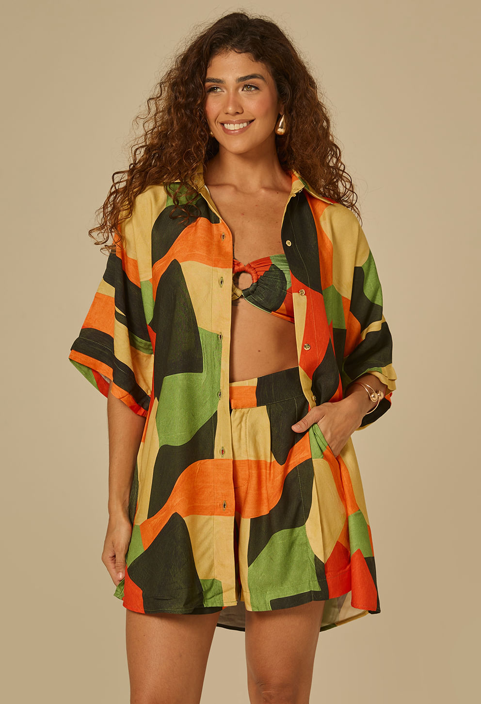 Camisão Lúcia Solare aberto mostrando look com biquíni, estampa geométrica multicolorida.