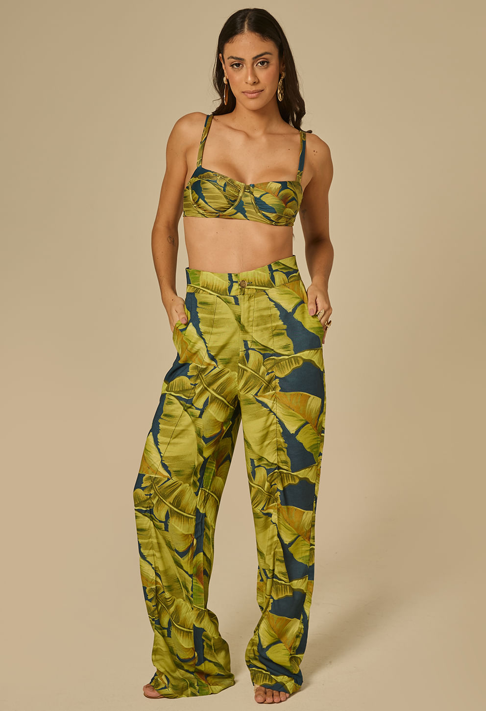 Foto frontal da calça Pantalona Thabata Quatro Folhas em estampa de folhas verdes e azuis, modelagem ampla e cintura alta.
