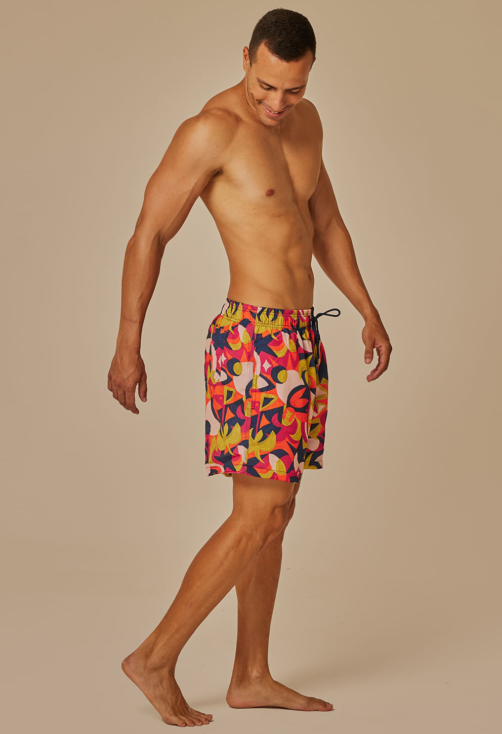 Vista lateral do modelo masculino usando bermuda shortinho Tropicália colorida.