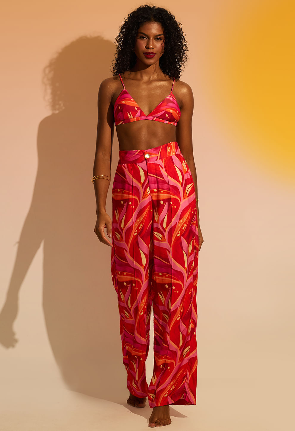 Calça pantalona rosa e vermelha com estampa de folhas, cintura alta e caimento amplo