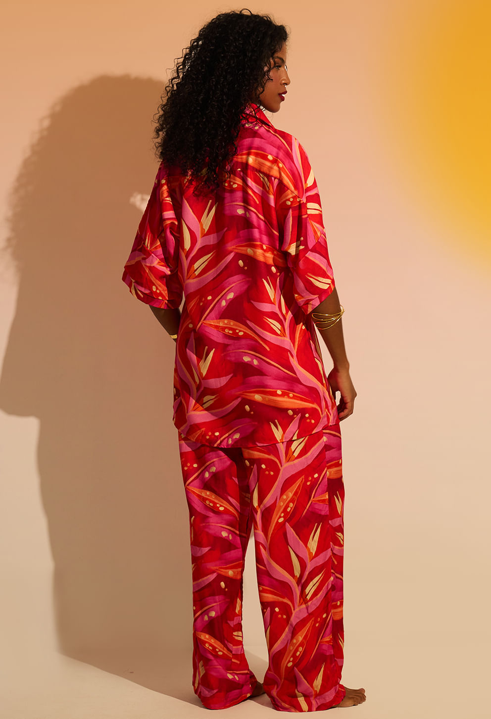 Visão traseira da modelo com camisão Lúcia rosa/vermelho, destacando caimento fluido e estampa folhagem.