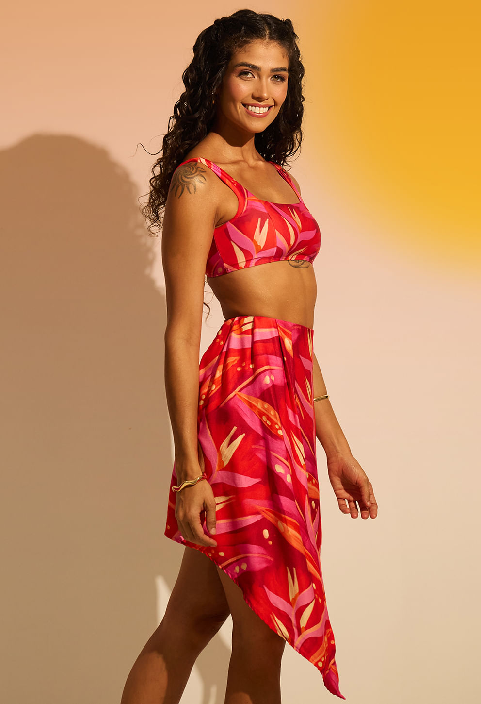 Perfil lateral da saia rosa/vermelha com estampa tropical e caimento fluido