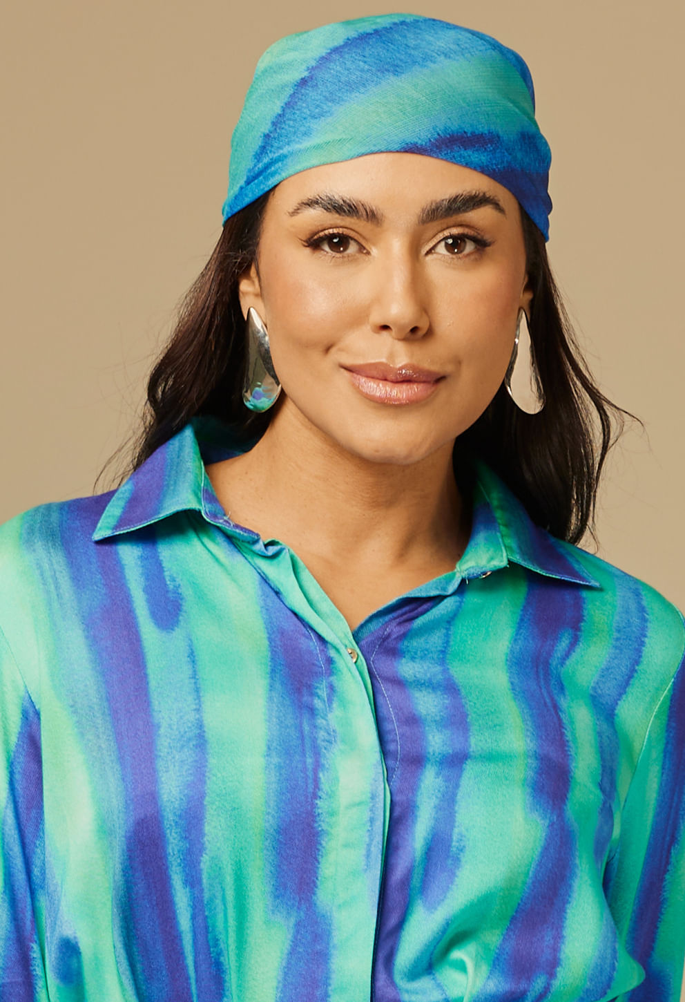 Mulher usando lenço Boreal azul e verde, amarrado na cabeça com padrão listrado aquarelado
