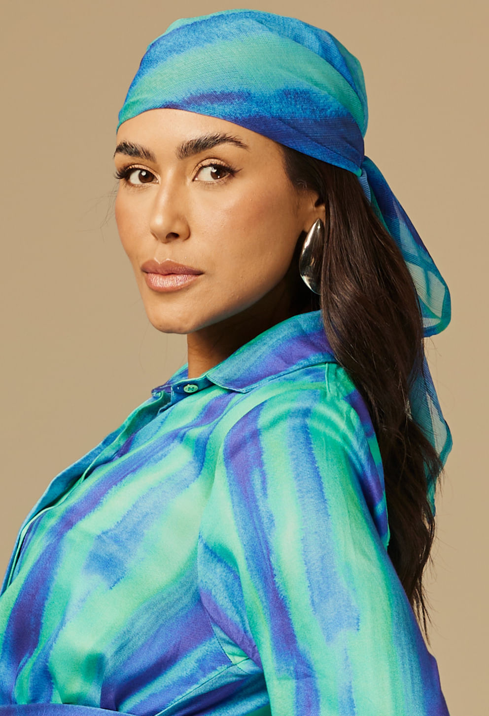 Mulher de perfil usando lenço Boreal azul e verde, amarrado na cabeça, com blusa combinando