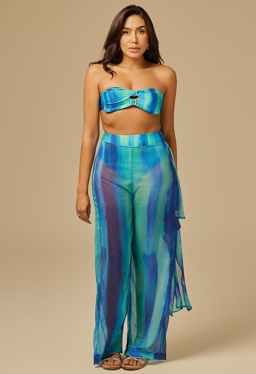 Modelo feminina usando calça amarração Boreal azul e verde com listras verticais, tecido leve e fluido.
