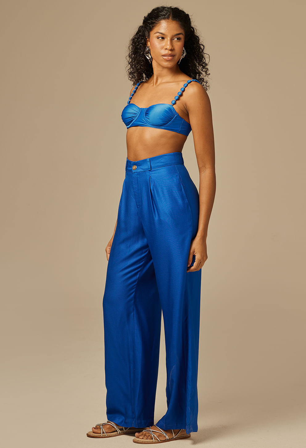 Vista lateral da calça pantalona social azul royal com cintura alta e pregas frontais
